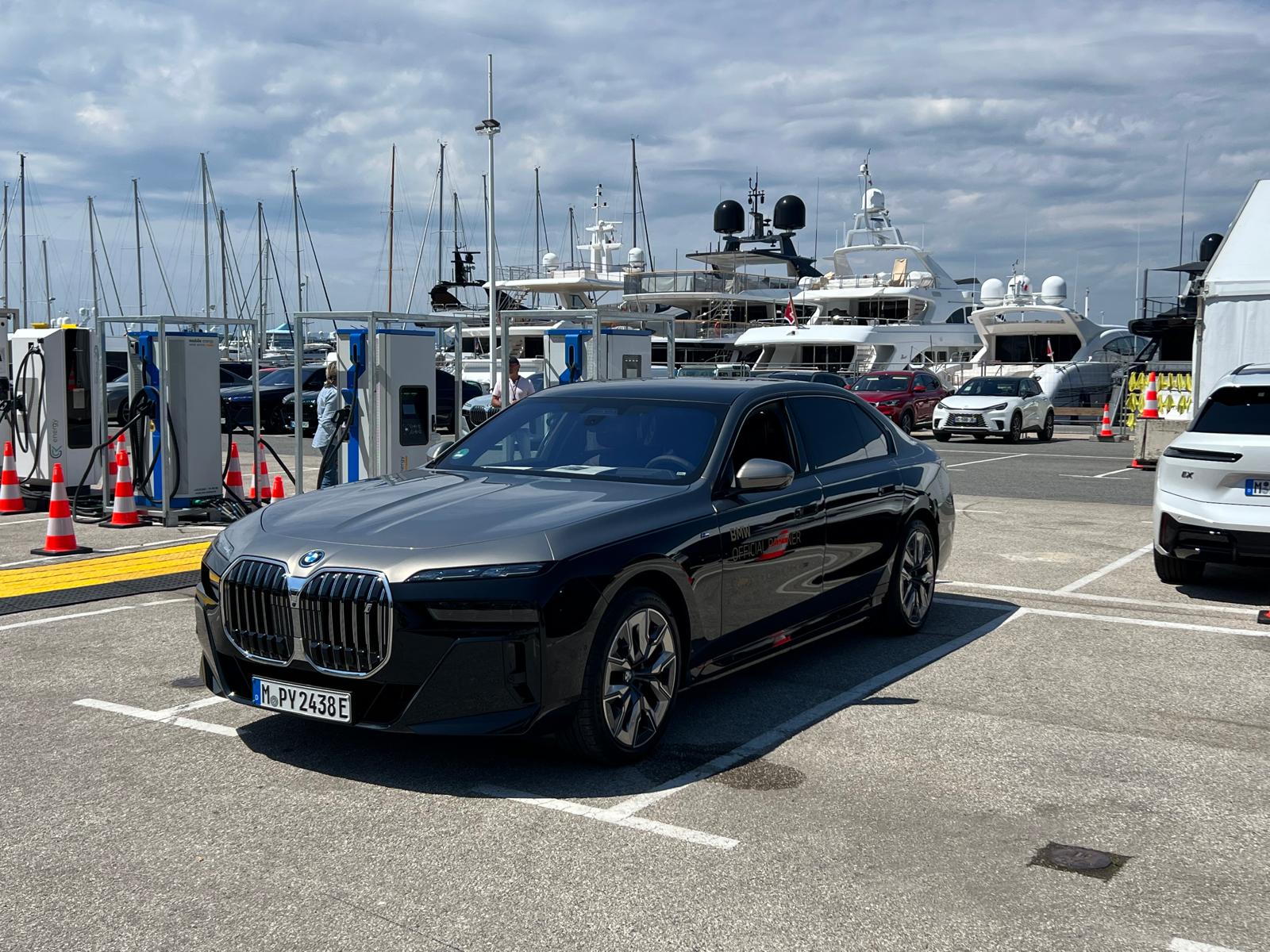 An all-electric BMW i7 charging on the port of Cannes between two red carpets