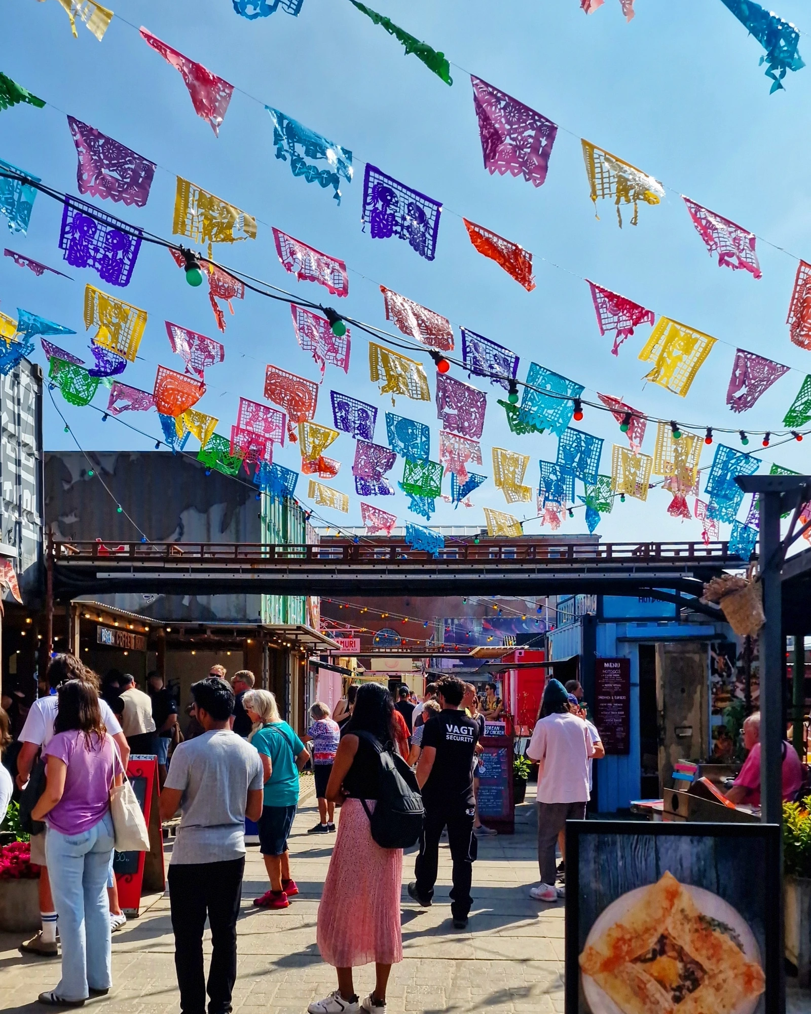 A busy food stall at Reffen street-food market in Copenhagen, with a queue in the sun