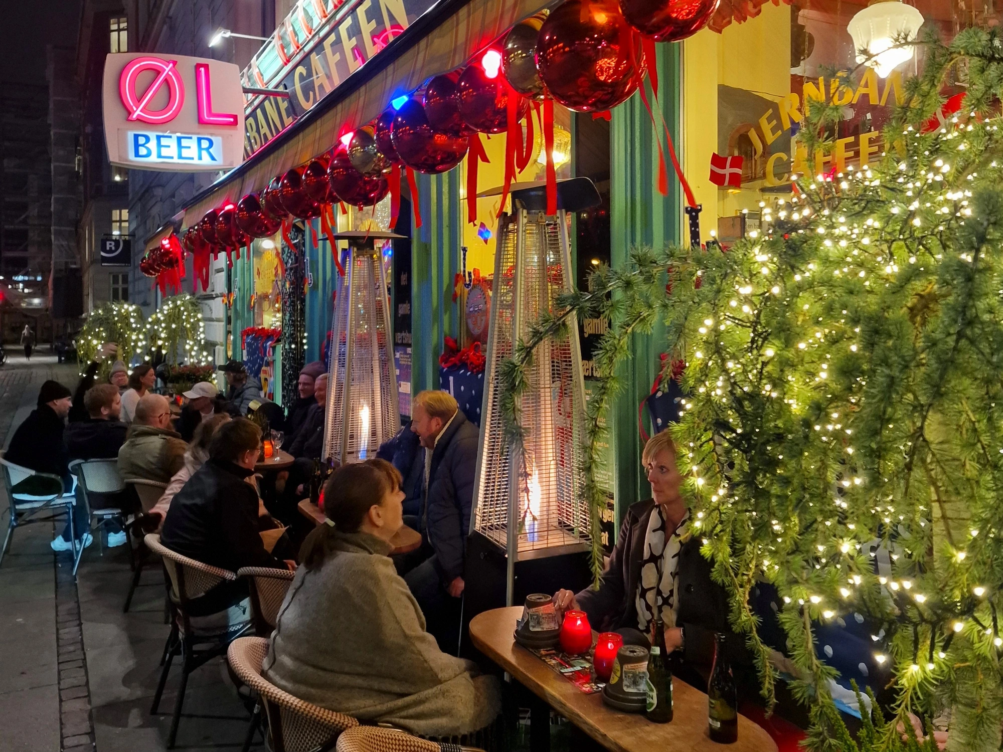 Copenhageners at an outdoor café under heat lamps and Christmas decorations
