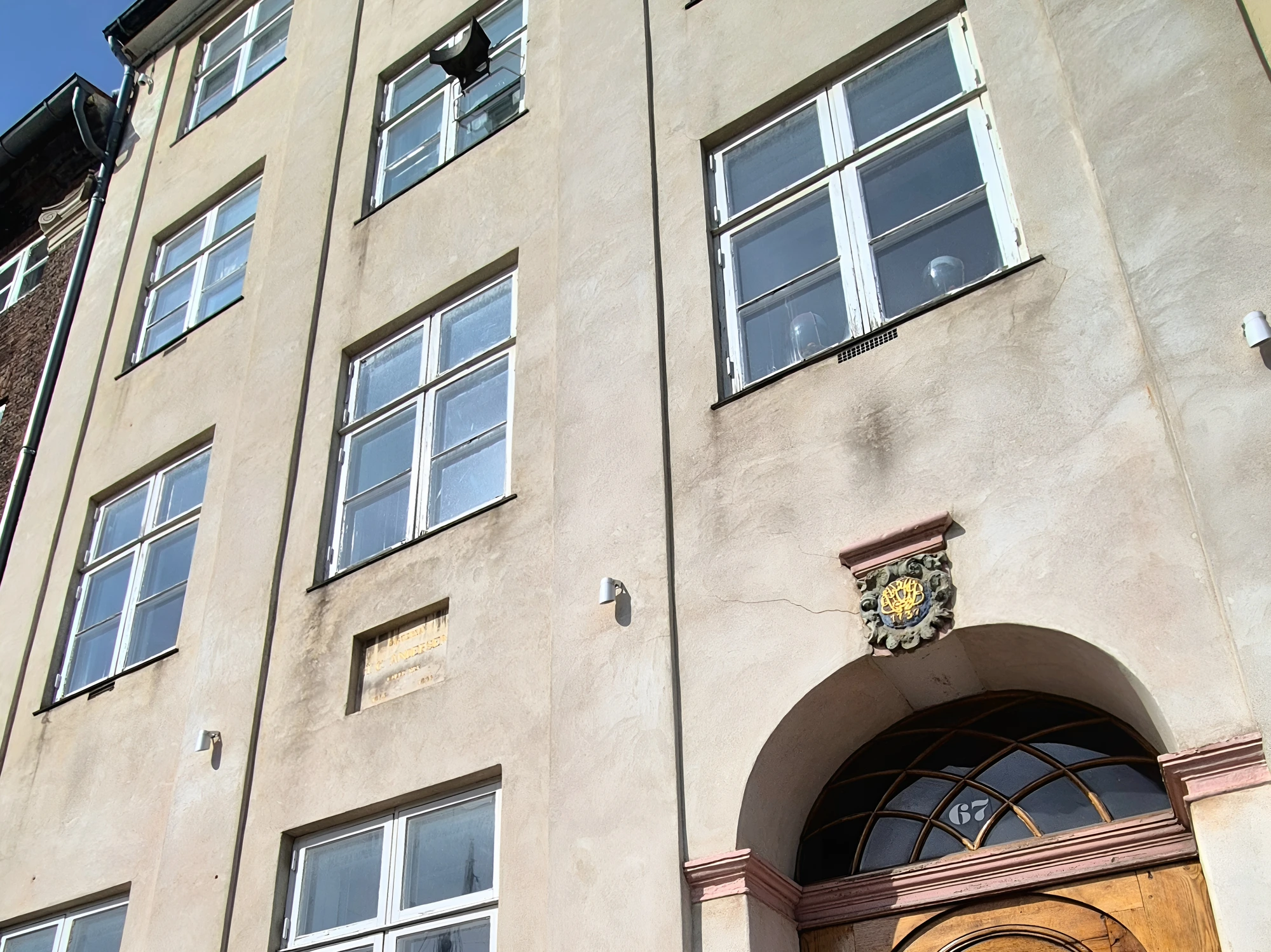 The arched wooden door of Nyhavn 67 with H.C. Andersen's memorial plaque