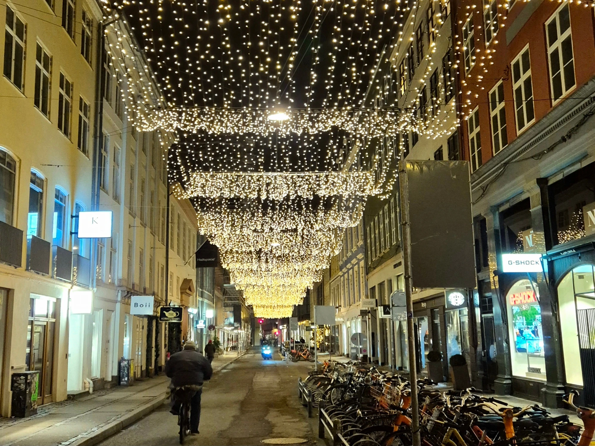 A giant chandelier of Christmas lights hanging over a Copenhagen shopping street