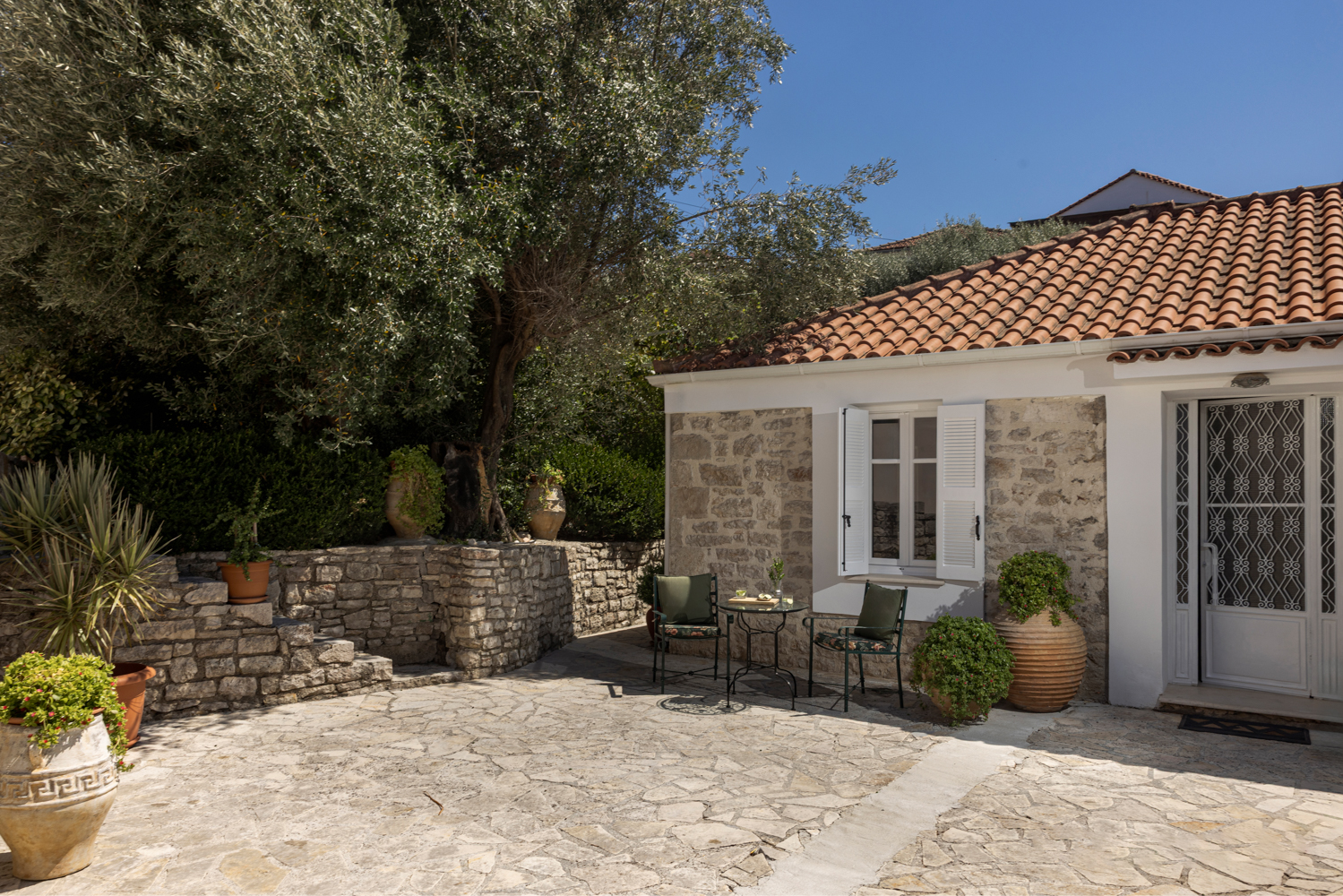 Open-plan interior — dining table, kitchen beyond, living room and doors out to the courtyard