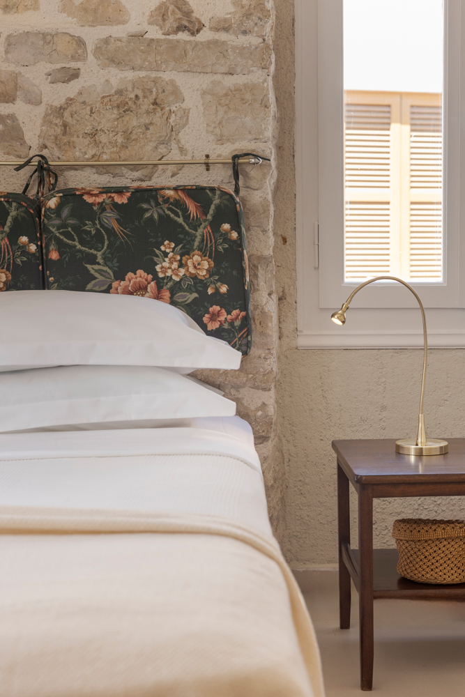 Second bedroom detail — brass gooseneck lamp against the exposed stone wall