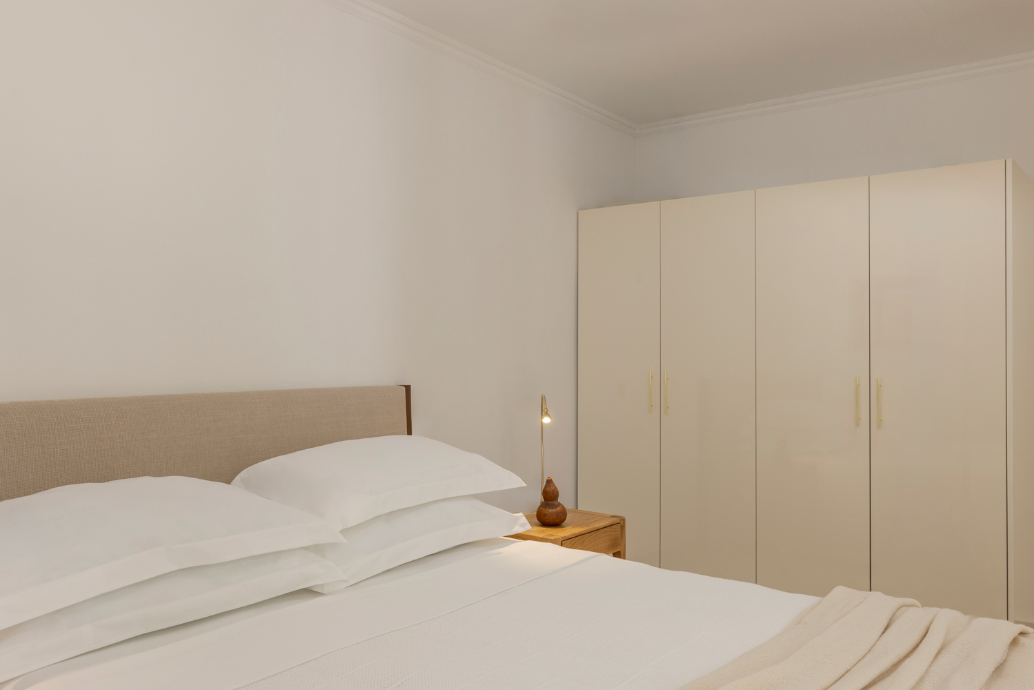 Primary bedroom with cream wardrobe and brass reading lamp