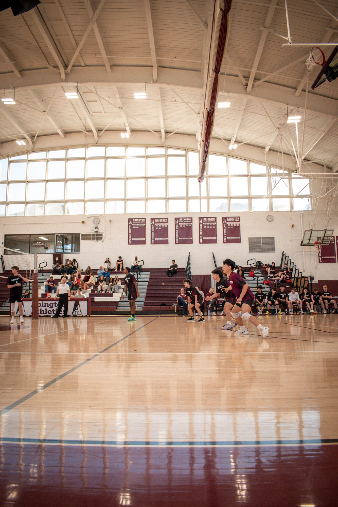 Volleyball match in a sunlit gymnasium