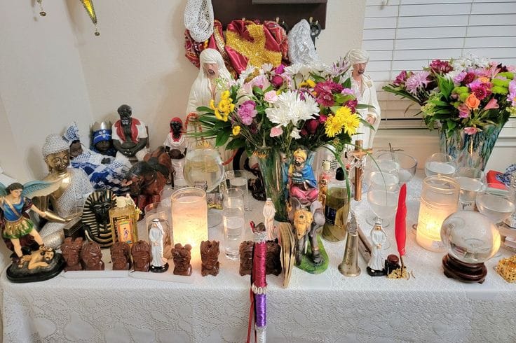 Bóveda espiritual de santería con muñeca conga, pañuelos de las 7 potencias africanas y aguas para el trabajo espiritista