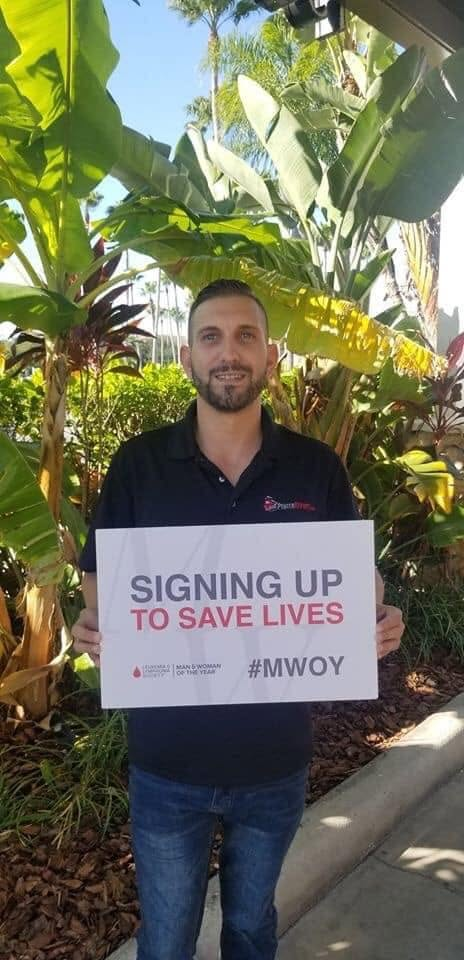 Greg holding a 'Signing up to save lives' #MWOY sign